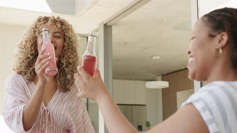 biracial women share a cheerful moment with drinks