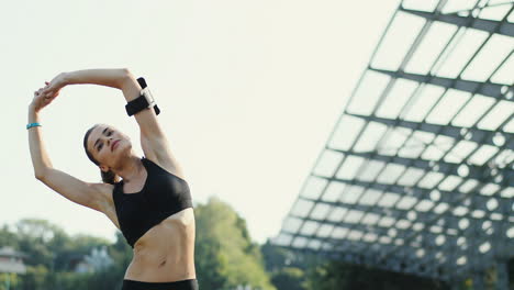 Young-Jogger-Woman-Training-And-Warming-Up-Hands-And-Shoulders-In-The-Stadium-In-Summer