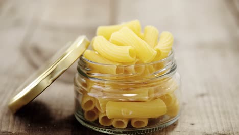 tube pasta in one little jar glass on wooden table with the lid