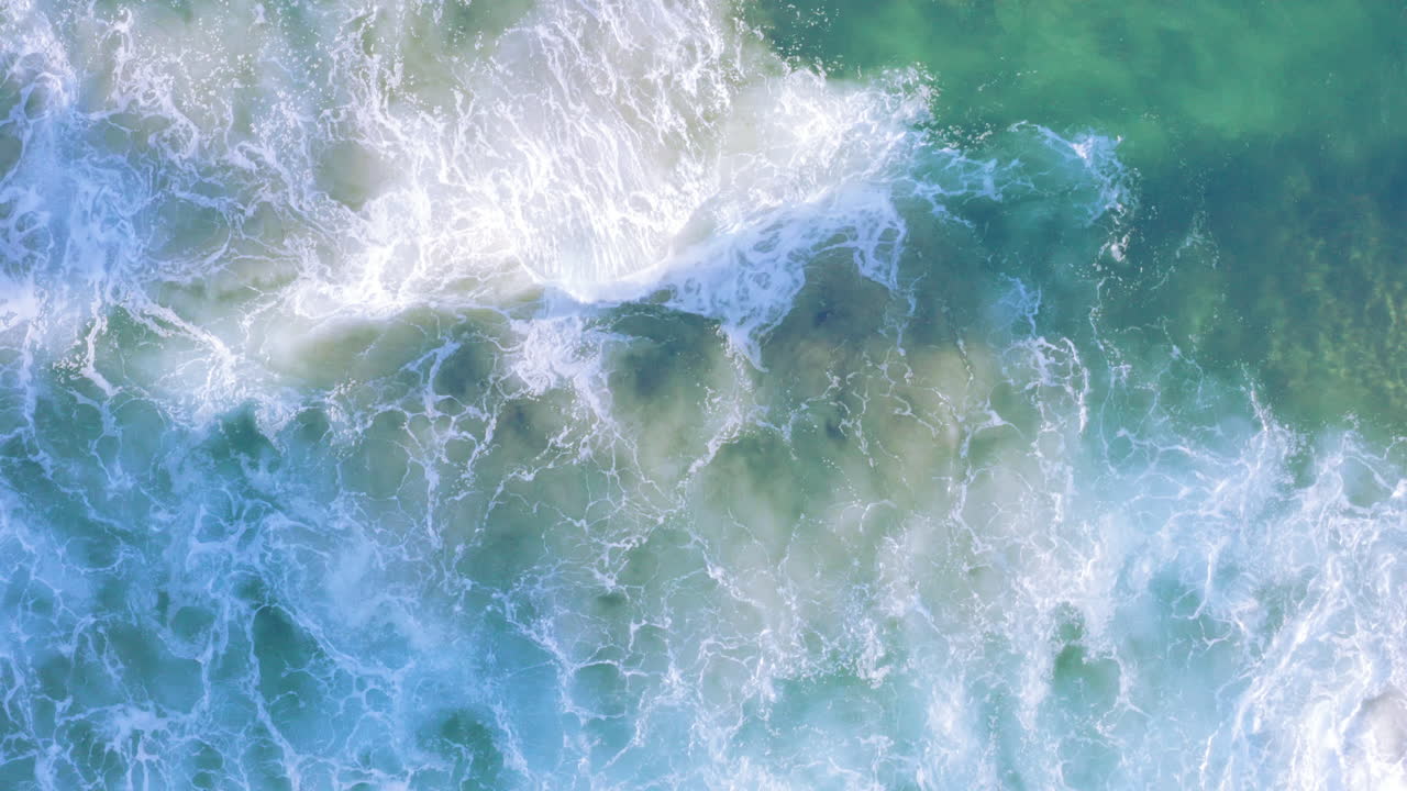 olas con flecos blancos rodando desde la parte superior de la pantalla hacia la costa arenosa poco profunda playa tamarama sydney australia drone pov