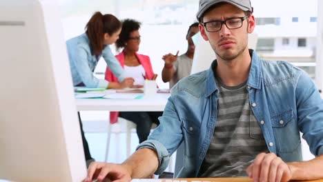 Designer-working-with-colleagues-talking-behind-him