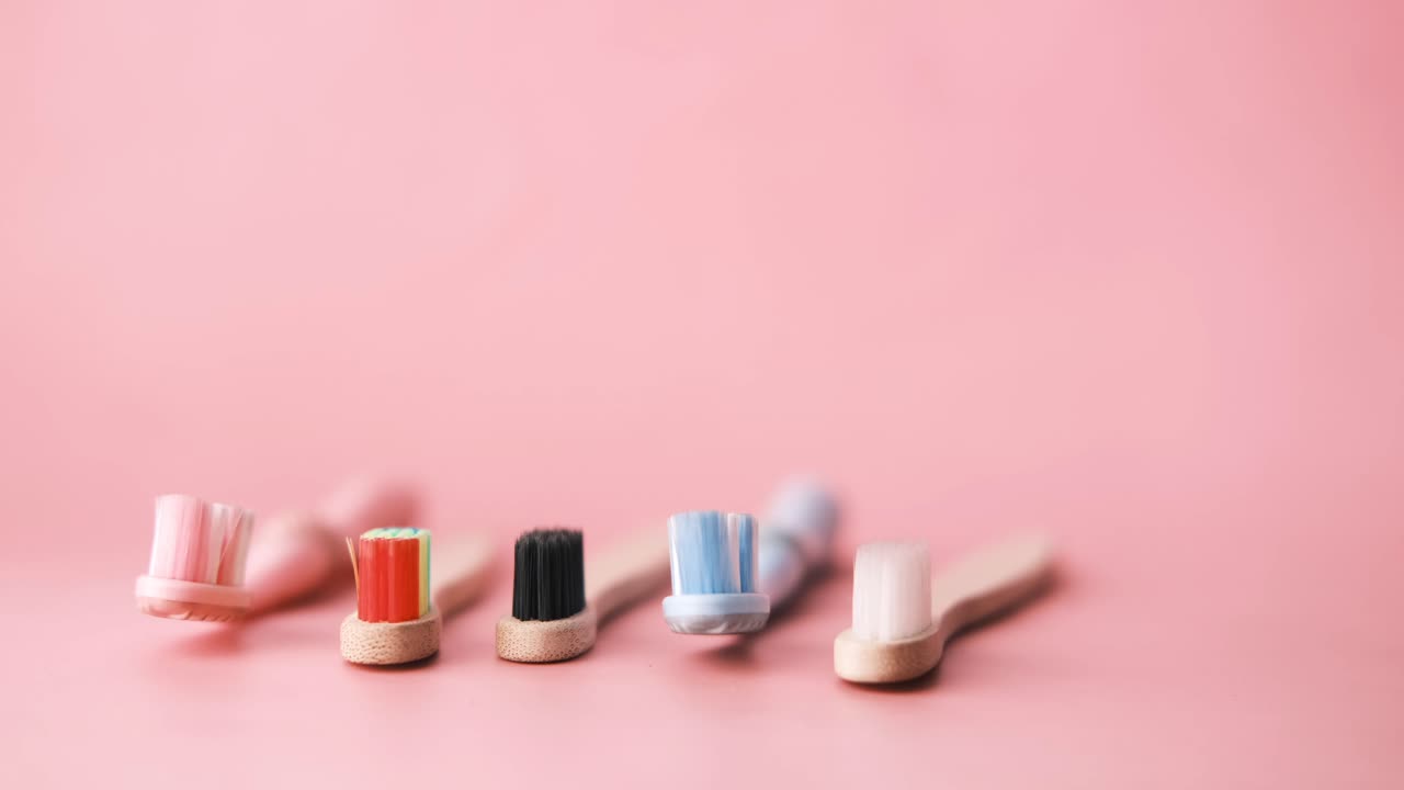 cepillos de dientes de bambú coloridos sobre un fondo rosado