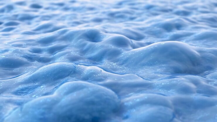 Una vista ravvicinata di una superficie d'acqua che mostra increspature e bolle serene, catturata da una prospettiva dall'alto. La scena è caratterizzata da toni naturali blu e bianchi, rendendola perfetta.
