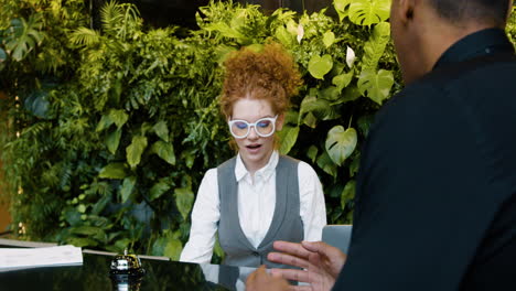 redheaded receptionist sitting behind the counter of a hotel