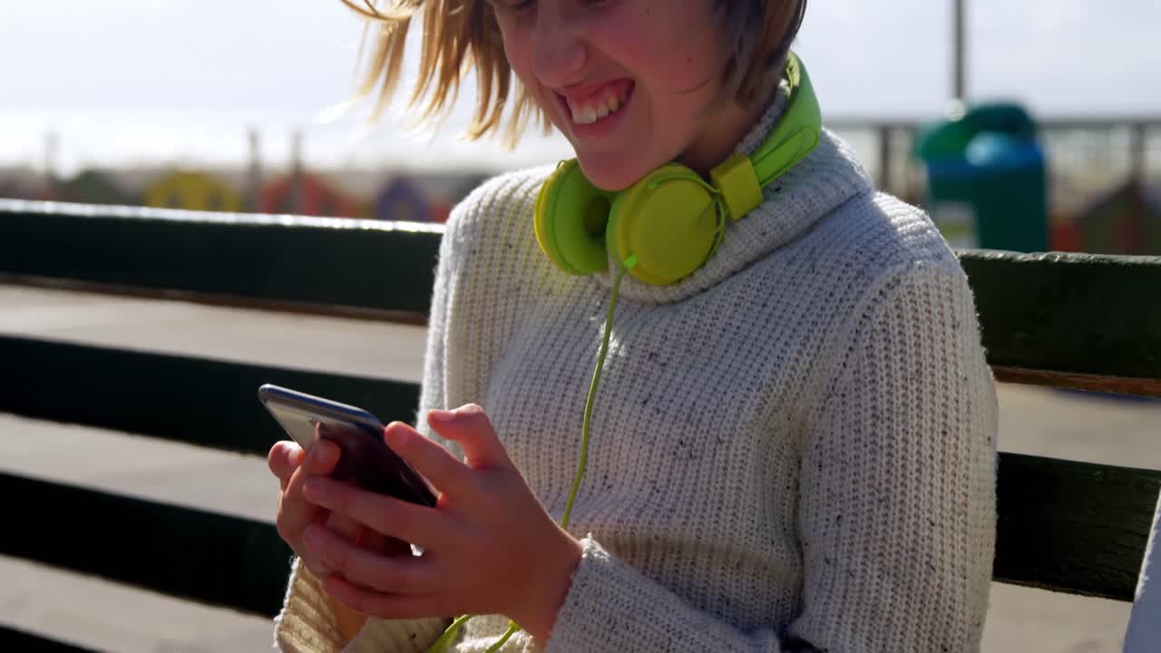 Teenage girl using mobile phone at beach 4k