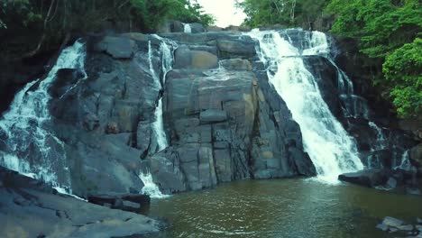 ascending aerial close shot of stunning waterfall and river in woods