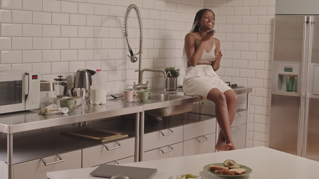 Donna afroamericana che parla al telefono in cucina