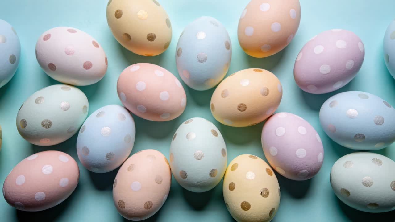 Pulling back camera revealing painted pastel polka-dot eggs on pale blue surface, showing layout