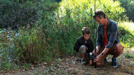 father teaching son to use fishing rod in the park