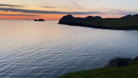 Twilight-hues-over-Heimaey-coastline,-Stórhöfði,-Iceland,-with-calm-sea-and-silhouetted-terrain