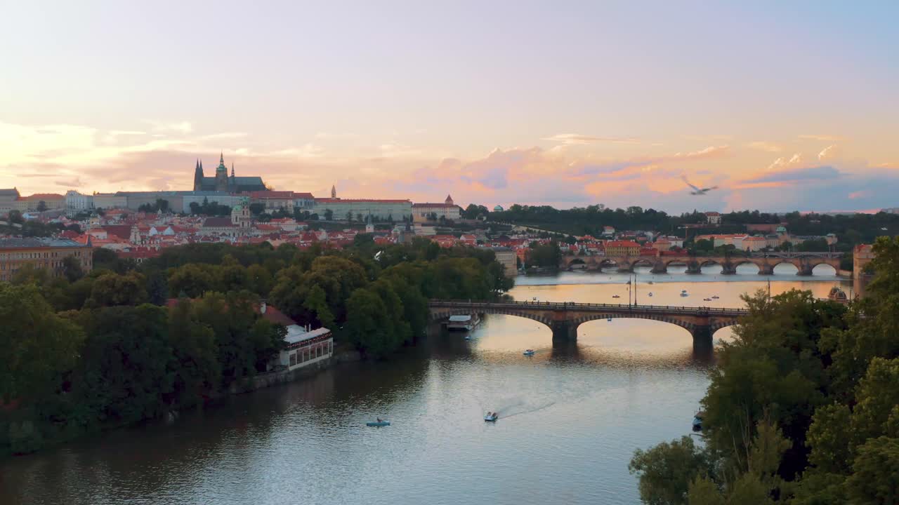 Drone over Charles Bridge Over Vltava River and Prague castle, boats Sailing On crystal clear Water At Sunset In Prague, Czech Republic. - aerial flight