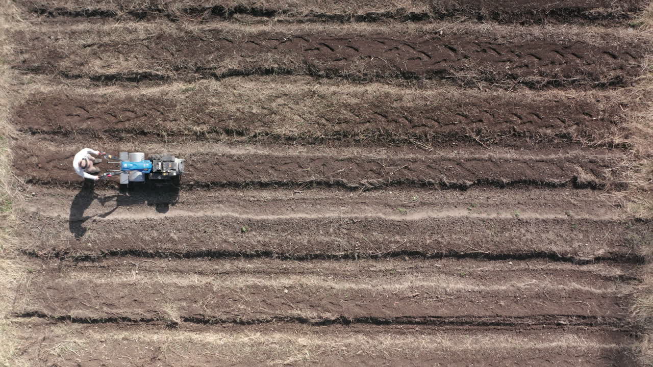 공중 - 로토틸러, 농업, 상승하는 와이드 샷으로 들판에서 일하는 남자