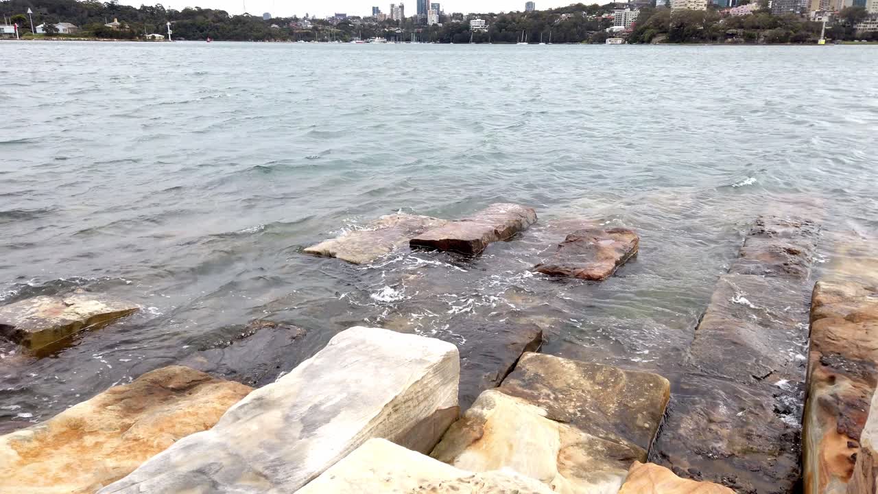 las olas del mar salpican grandes bloques de arenisca en barangaroo, sydney, nsw, australia