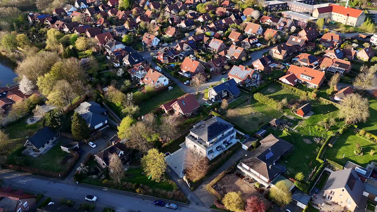 Luxury housing area with villas and one family houses near lake. Sunset time in american small town. Aerial top down shot. Spring day with green trees and grass in garden.