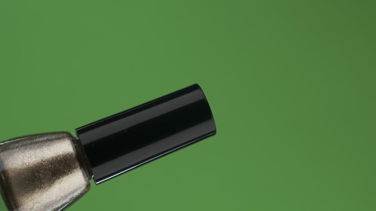 rotación diagonal de una botella de vidrio de esmalte de uñas. aislado en verde.