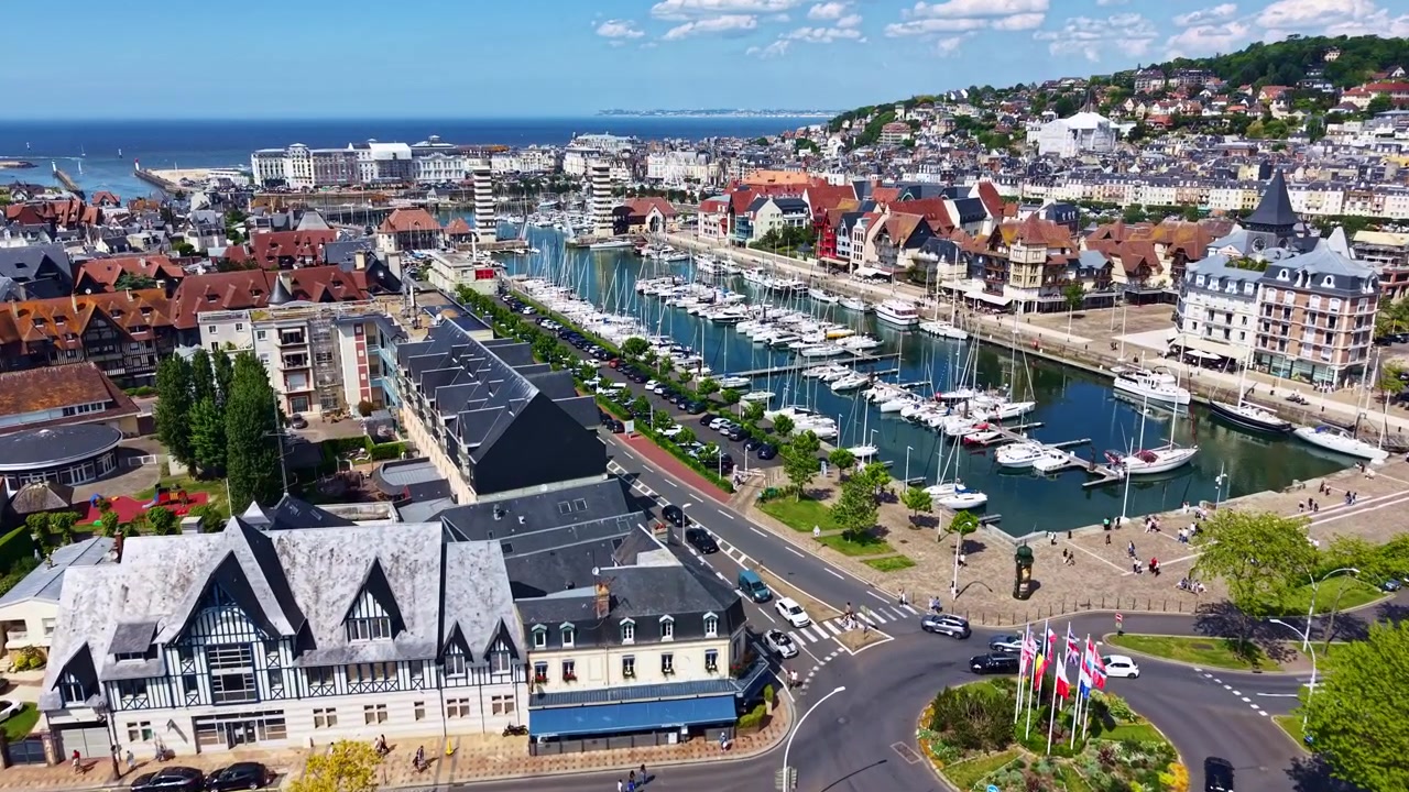 Úžasný dron letí směrem k Jachetnímu bazénu, známému také jako Bassin des Yachts, pobřežnímu přístavu obce Deauville za slunečného dne, Calvados, Francie.