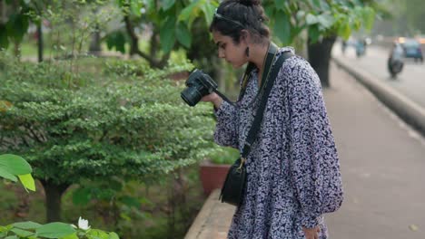 a woman photographer taking photos of a flower outdoors during the daytime