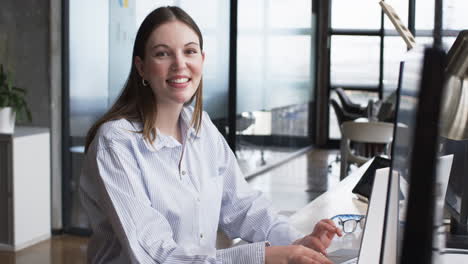 Young-Caucasian-woman-with-brown-hair-works-at-computer-in-an-office-setting,-handling-her-business-