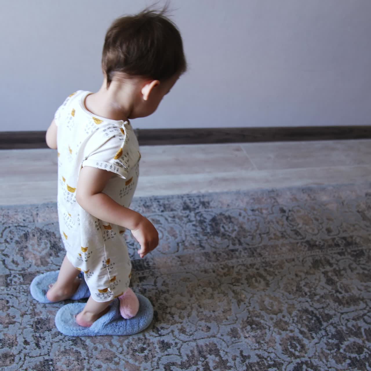 Lovely little kid wearing blue fluffy slippers crosses the room. Kid borrowed his mom's footwear