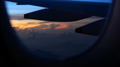 pov: airplane passenger looks out window, view of sunrise, sunset, clouds, wing