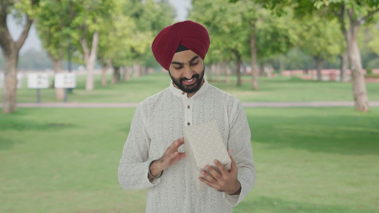 hombre indio sikh feliz recibiendo un regalo en el parque