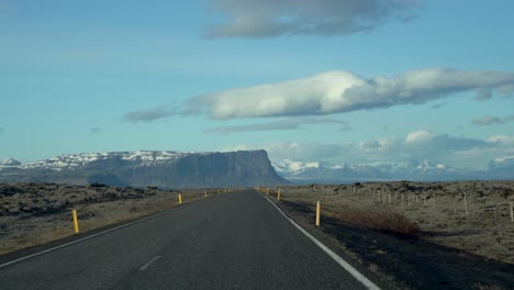 driving perspective on an open road in iceland with vast skies and distant mountains