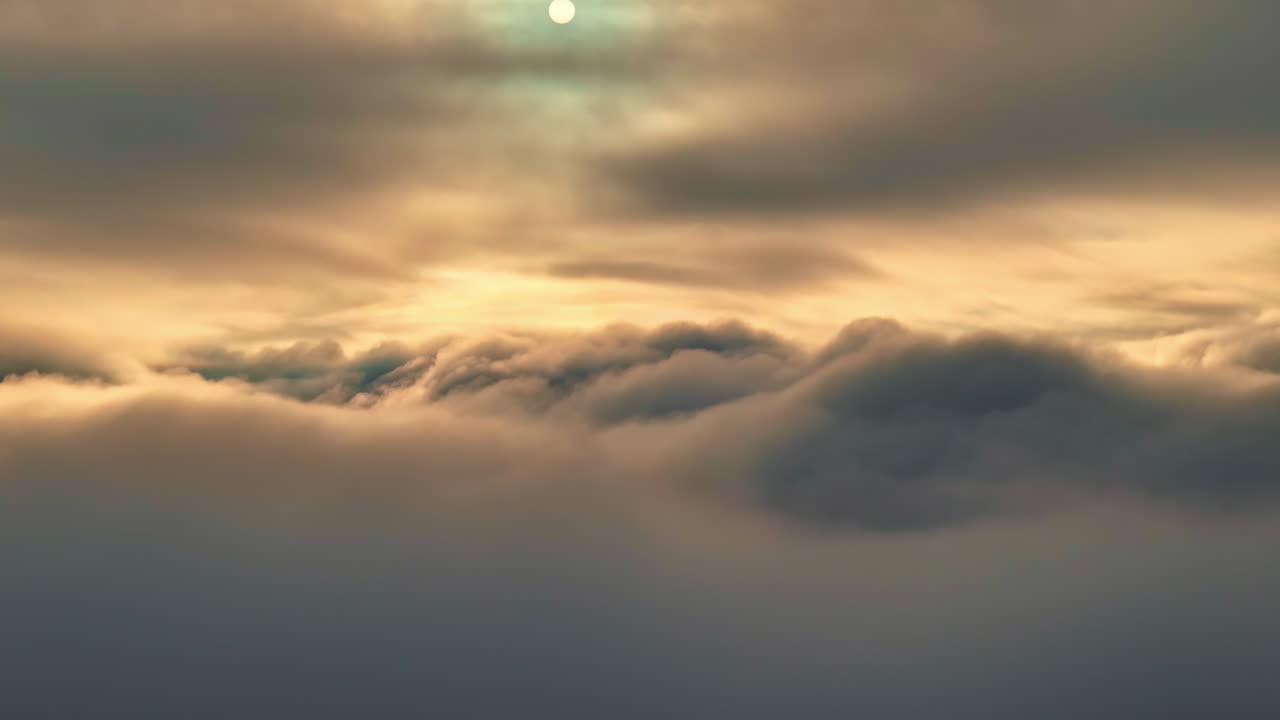 Aerial view of thick, rolling clouds with soft sunlight filtering through the sky