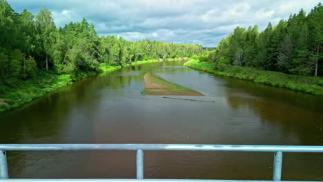 van parked on the bridge over the river between the lush green trees during daytime