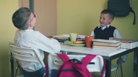 los escolares cenan en la mesa con libros de texto en la cantina