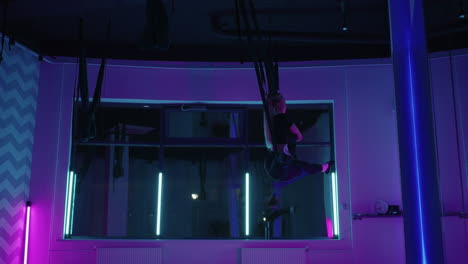 estirando en hamaca para el yoga aéreo en la sala de gimnasia mujer está entrenando en el club de fitness solo