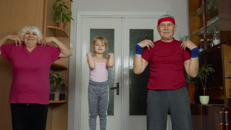 granddaughter and mature grandparents in sportswear making sports jogging workout exercises at home