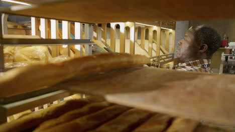 baker arranging bread on shelves in a bakery