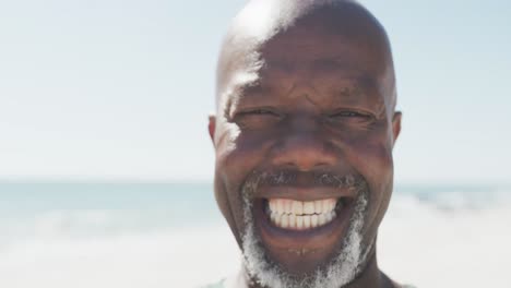 portrait of happy senior african american man smiling at beach with copy space, in slow motion