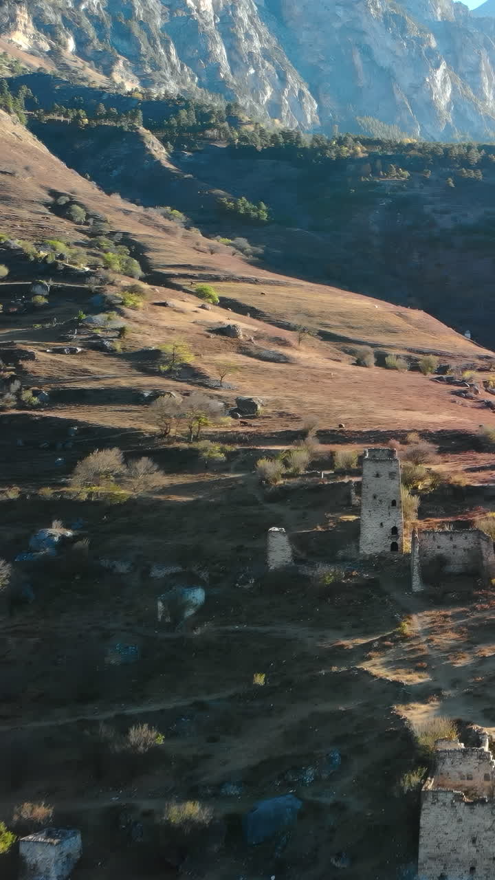 Vista aerea di antiche torri di pietra in una valle montuosa impervia.