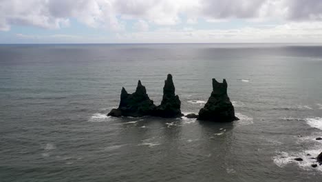 rocks in the atlantic ocean in vik, iceland with drone video pulling out