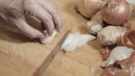 chef cutting white onion into thin slices with a sharp knife in rapid motion, close up, high angle