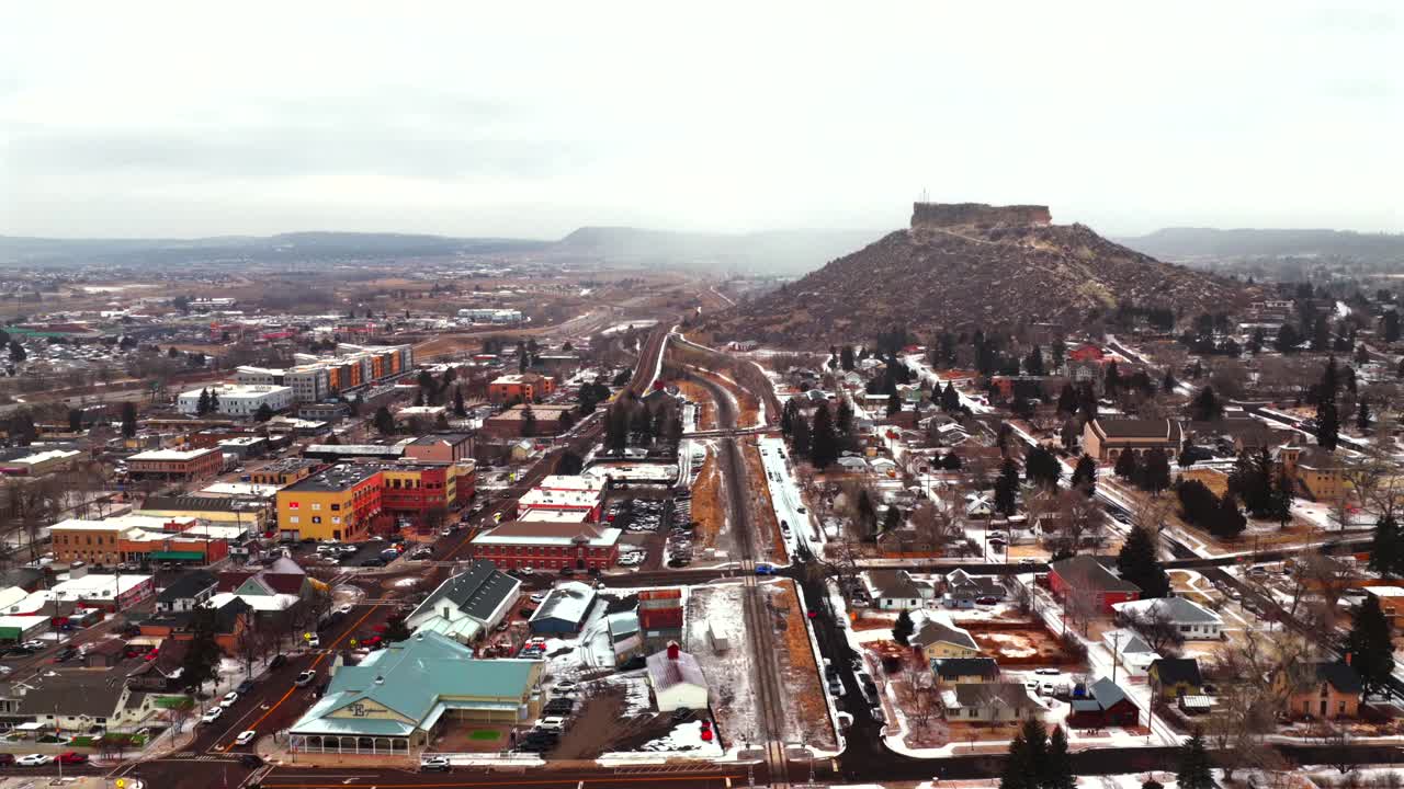 Castle Rock Colorado, dron aéreo, Front Range, ciudad al sur de Denver, meseta cubierta de nieve, mañana de invierno nevada, día nublado nevando, coches, vía de tren, edificio, barrio, centro, movimiento de paneo hacia atrás.