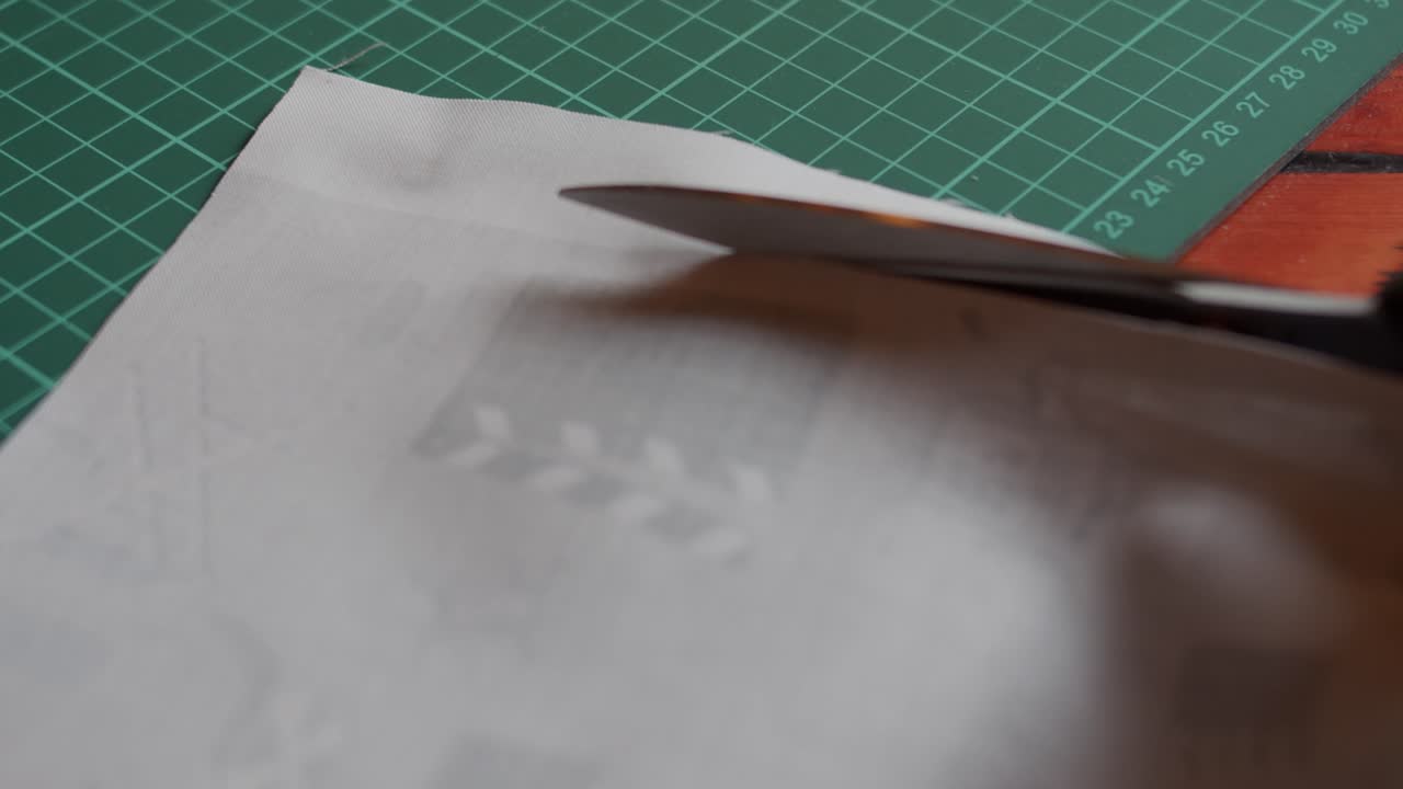 Close up of cutting through fabric with scissors on a table.