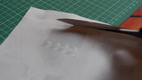close up of cutting through fabric with scissors on a table.