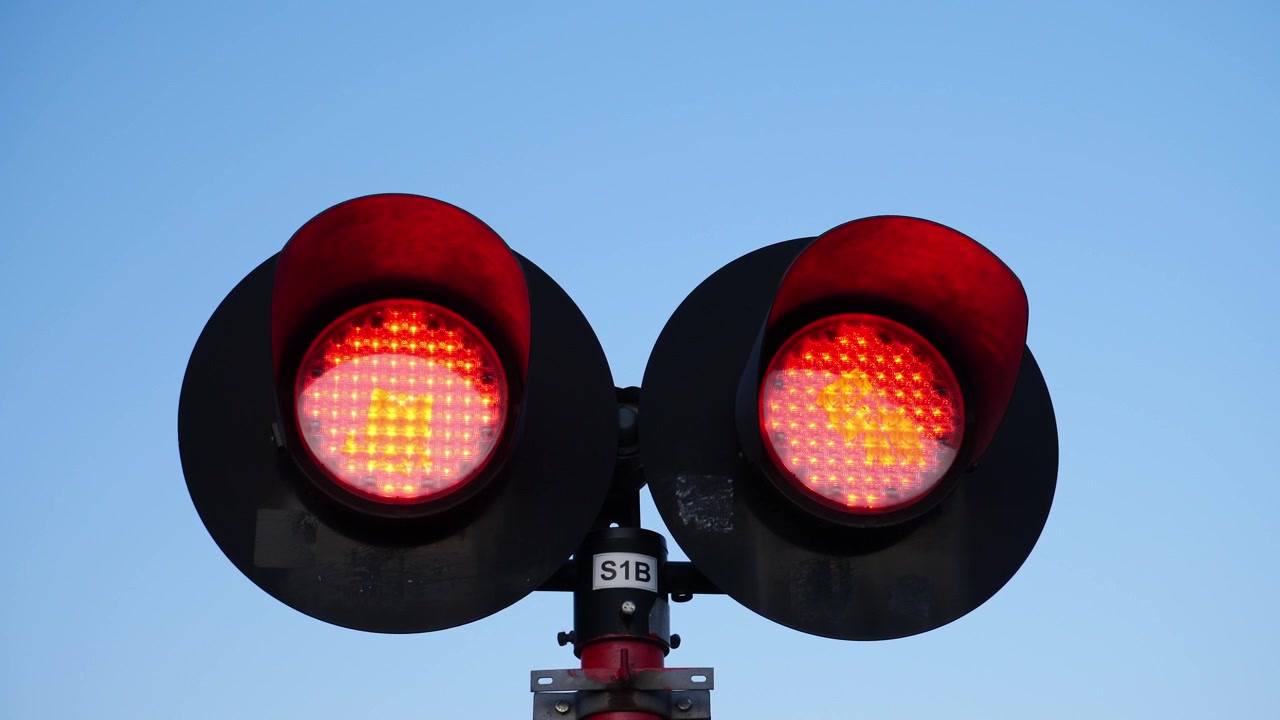 Luzes piscando alternadamente em uma passagem de nível ao anoitecer. Władysławowo, Polônia.