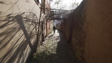 Mujer-Caminando-Sola-En-Una-Pequeña-Calle-Adoquinada-En-La-Ciudad-Turística-Medieval-De-Francia,-Kaysersberg