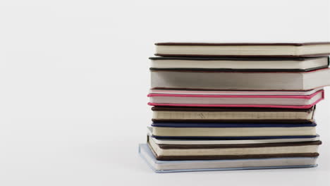 una pila de libros de tapa dura en varios colores se inclina ligeramente hacia el lado, con espacio de copia