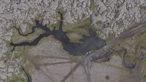 Aerial-above-Icelandic-landscape-with-river-and-adventurous-dirt-road