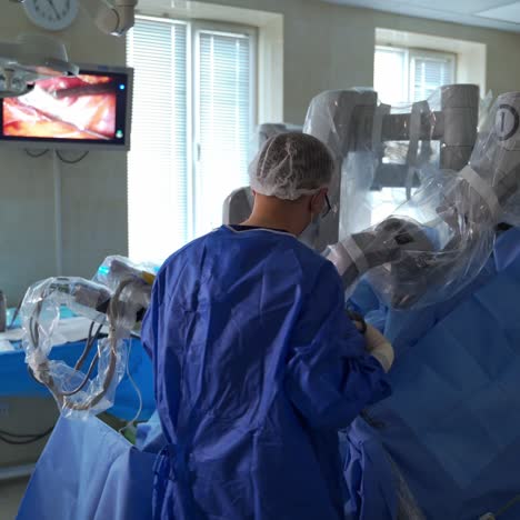 surgeon stands with his back to the camera. doctor performing operation using da vinci robot. screen showing the place of invasion