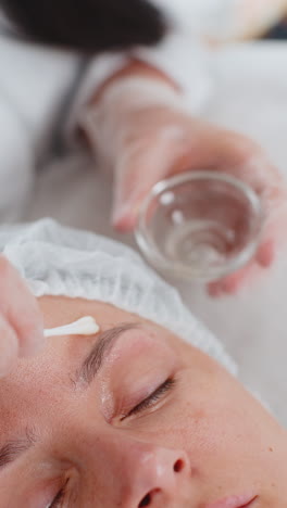 cosmetólogo aplicando ácido pelador hidratante en la piel alrededor de los ojos de la mujer tratamiento antienvejecimiento