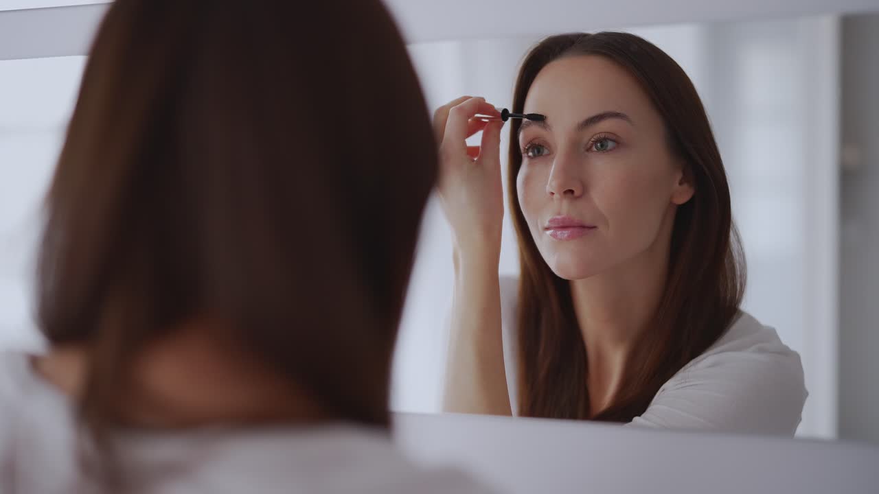 mujer aplicando maquillaje de cejas frente al espejo