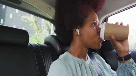 african american businesswoman drinking takeaway coffee in car