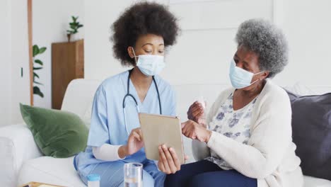 african american female doctor and senior female patient in face masks