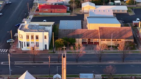 aerial camera smoothly pans across a quiet town intersection in coonabarabran, new south wales, australia, during early morning golden hour lighting