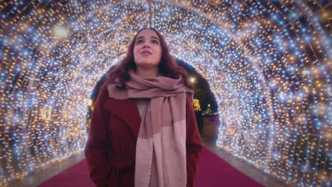 girl walks through a beautiful tunnel of christmas lights slow motion wide shot